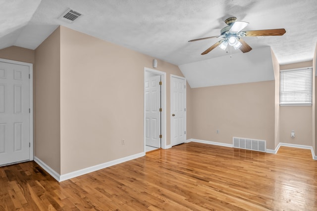 additional living space with light wood-type flooring, visible vents, and baseboards