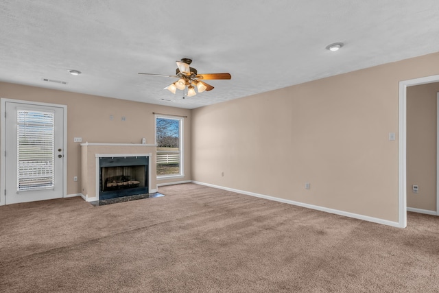 unfurnished living room featuring visible vents, a fireplace with flush hearth, carpet floors, baseboards, and ceiling fan