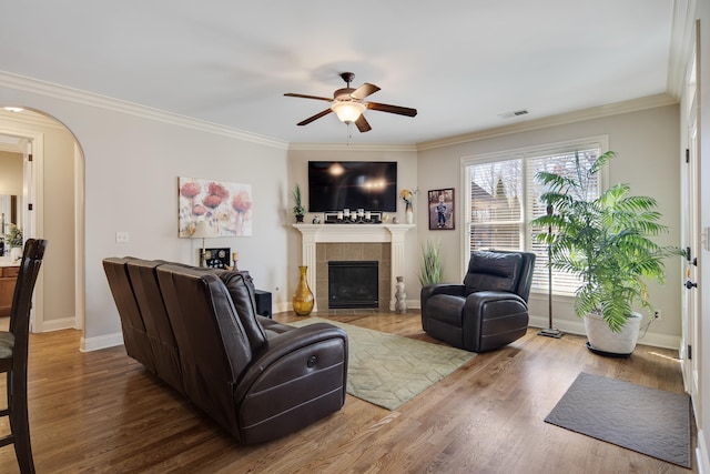 living room featuring arched walkways, visible vents, a tile fireplace, and wood finished floors