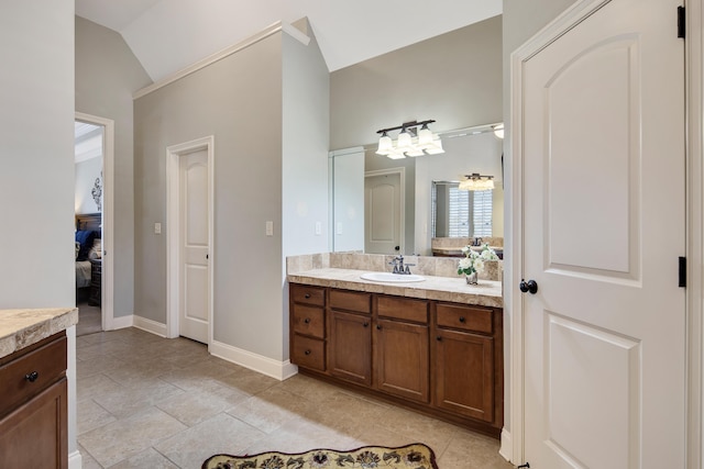 ensuite bathroom with connected bathroom, lofted ceiling, baseboards, and vanity