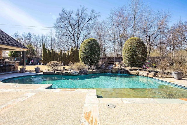 outdoor pool featuring a patio area, a fenced backyard, and outdoor dry bar