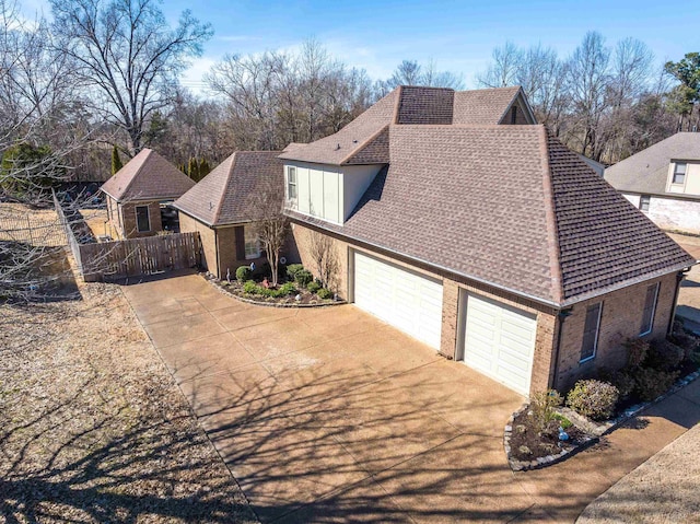 exterior space with concrete driveway, an attached garage, fence, and brick siding