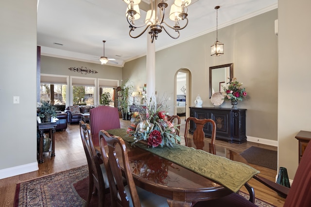 dining room with crown molding, wood finished floors, baseboards, and arched walkways