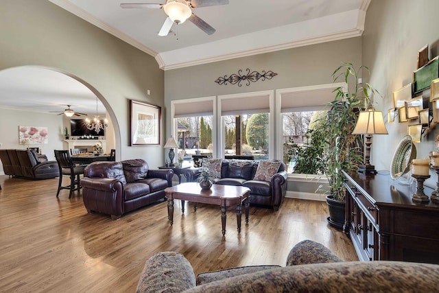 living room featuring arched walkways, wood finished floors, a ceiling fan, and crown molding