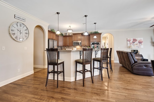 kitchen with a breakfast bar, open floor plan, arched walkways, and appliances with stainless steel finishes