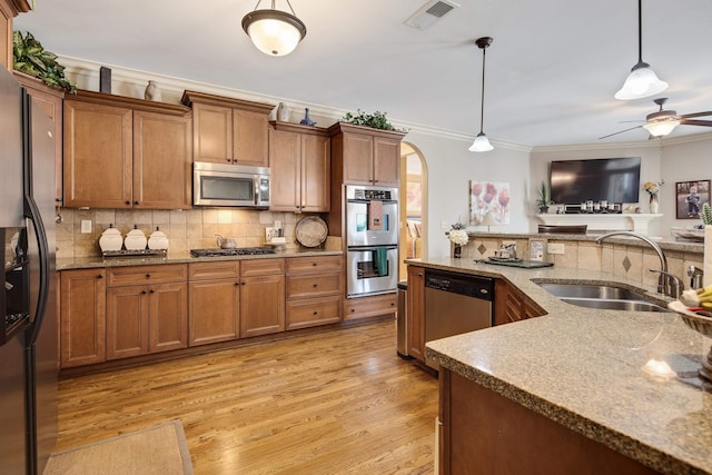 kitchen featuring tasteful backsplash, ornamental molding, arched walkways, stainless steel appliances, and a sink