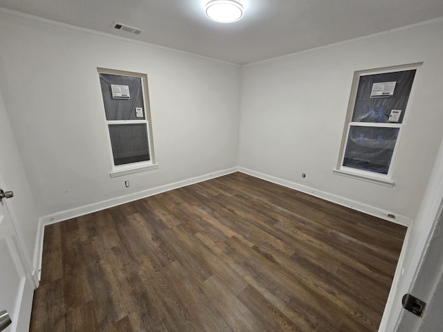 empty room featuring visible vents, crown molding, baseboards, and dark wood-style flooring