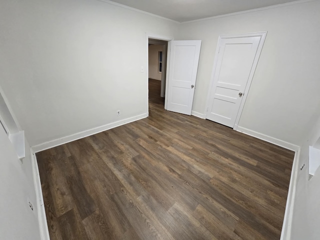 unfurnished bedroom with dark wood-style floors, crown molding, and baseboards