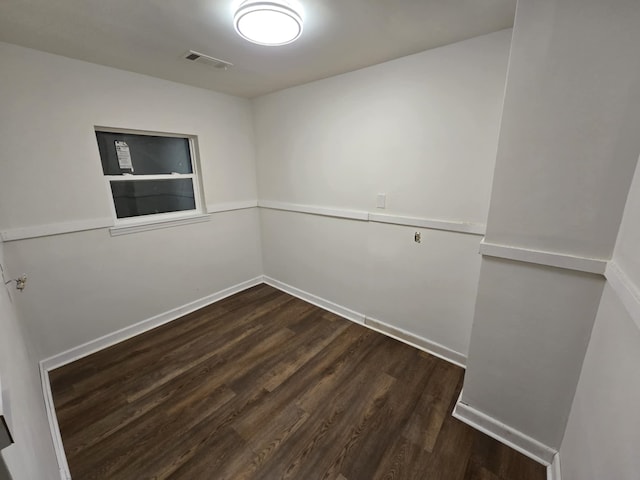 empty room featuring visible vents, baseboards, and dark wood-style flooring