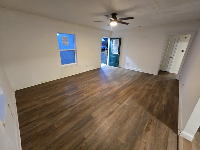 unfurnished room with ceiling fan, baseboards, and dark wood-style floors