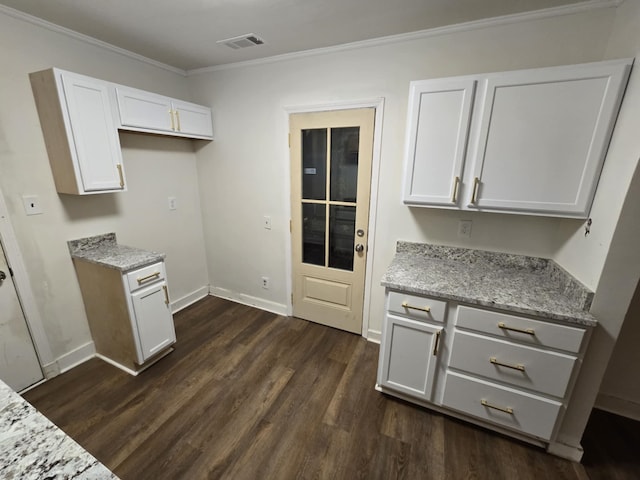 kitchen with light stone counters, visible vents, dark wood-style floors, and ornamental molding