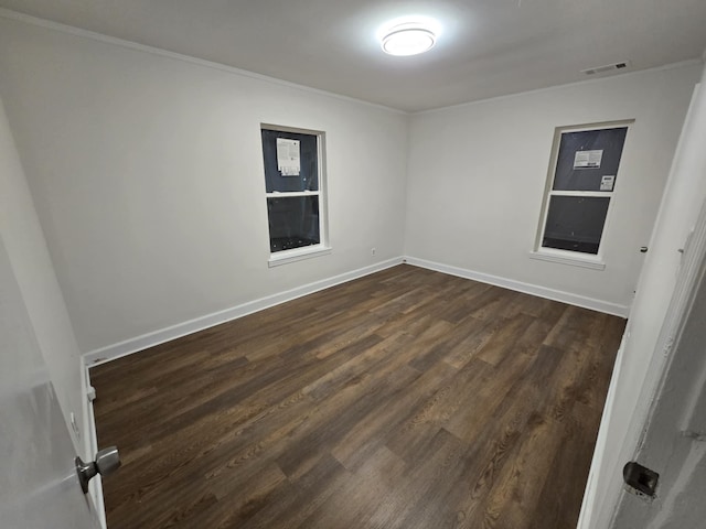 empty room featuring visible vents, baseboards, and dark wood-type flooring