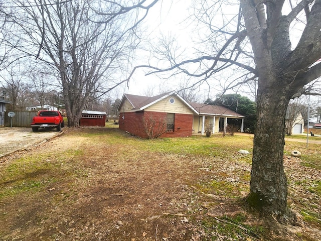 view of front facade featuring brick siding, driveway, and a front yard