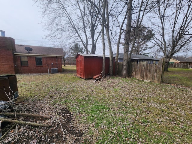 view of yard featuring a storage unit, central air condition unit, an outdoor structure, and fence