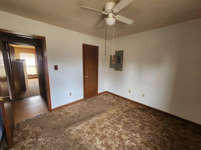 unfurnished bedroom featuring stone finish floor, electric panel, a textured ceiling, baseboards, and ceiling fan