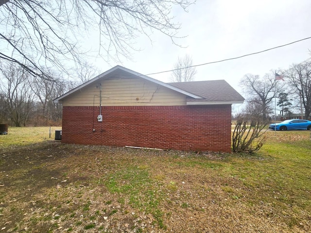 view of side of property with brick siding and a lawn