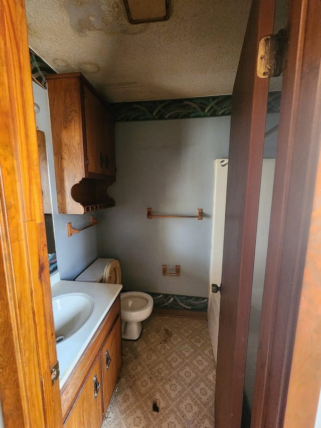 bathroom with vanity, toilet, and a textured ceiling