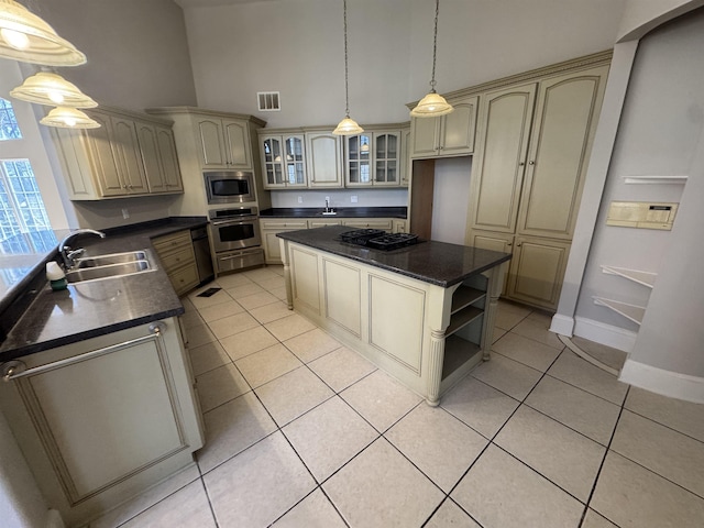 kitchen with visible vents, a sink, cream cabinets, dark countertops, and stainless steel appliances