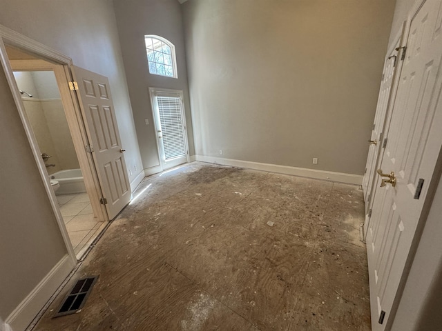 entrance foyer with visible vents, baseboards, and a high ceiling