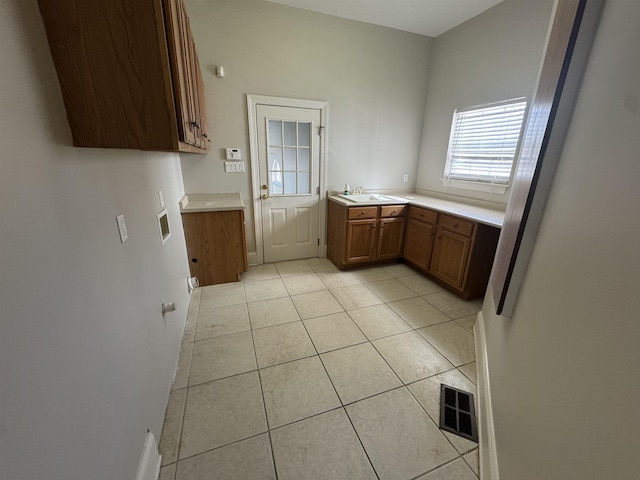 kitchen with light tile patterned flooring, visible vents, brown cabinets, and light countertops