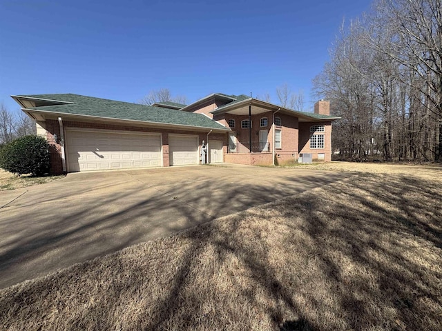 view of front facade featuring an attached garage, brick siding, driveway, and a chimney