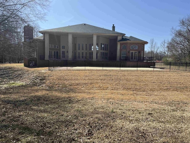 rear view of property featuring a yard, a chimney, and fence