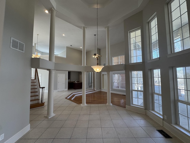 unfurnished dining area featuring tile patterned floors, visible vents, stairway, and ornate columns