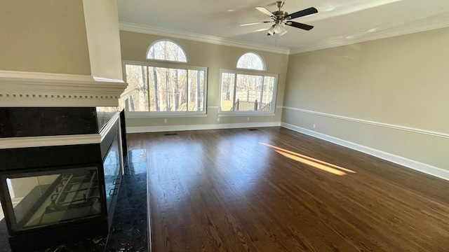 unfurnished living room featuring baseboards, crown molding, dark wood-type flooring, and a ceiling fan