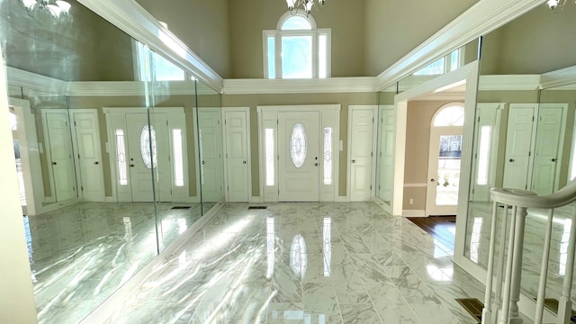 foyer entrance featuring baseboards, a high ceiling, and marble finish floor