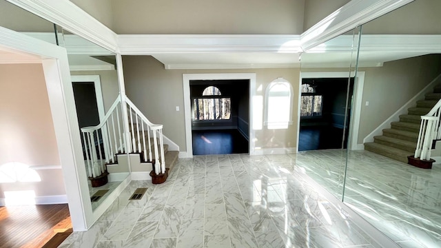 foyer featuring visible vents, baseboards, ornamental molding, stairs, and marble finish floor