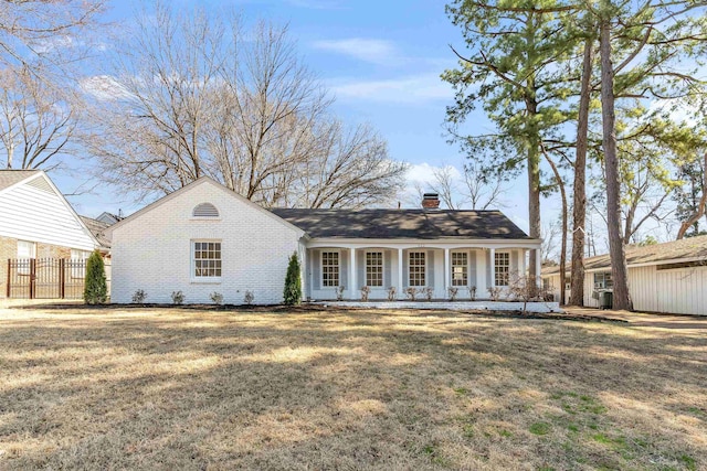 view of front facade featuring a front yard, fence, a porch, a chimney, and brick siding