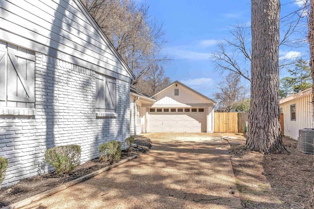 view of side of home featuring cooling unit, brick siding, a garage, and fence