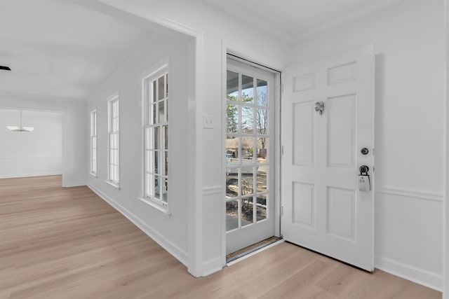 foyer featuring crown molding, light wood-type flooring, and baseboards