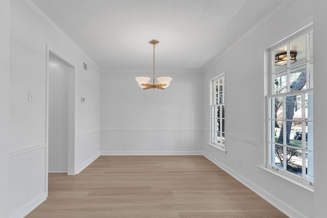 unfurnished dining area with an inviting chandelier, crown molding, baseboards, and light wood finished floors