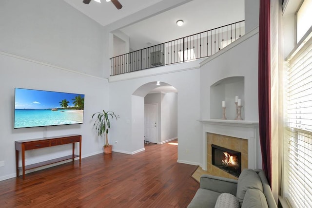 living room with ceiling fan, baseboards, a fireplace, wood finished floors, and arched walkways