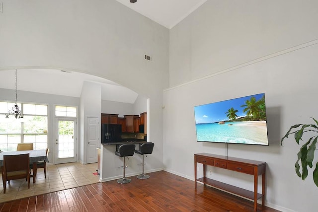 living room featuring visible vents, baseboards, high vaulted ceiling, dark wood finished floors, and arched walkways