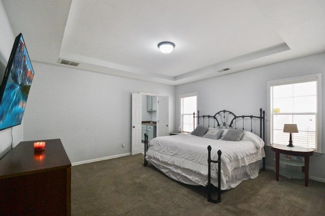 bedroom featuring a raised ceiling, baseboards, and dark carpet