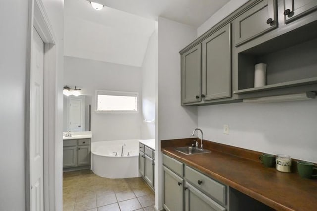 interior space featuring a bath, tile patterned flooring, vanity, and vaulted ceiling