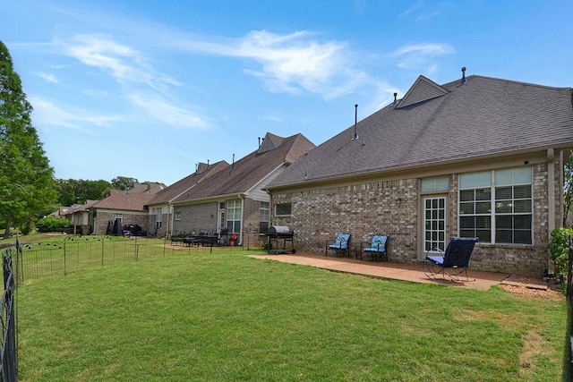 back of property with brick siding, a lawn, a patio, and fence