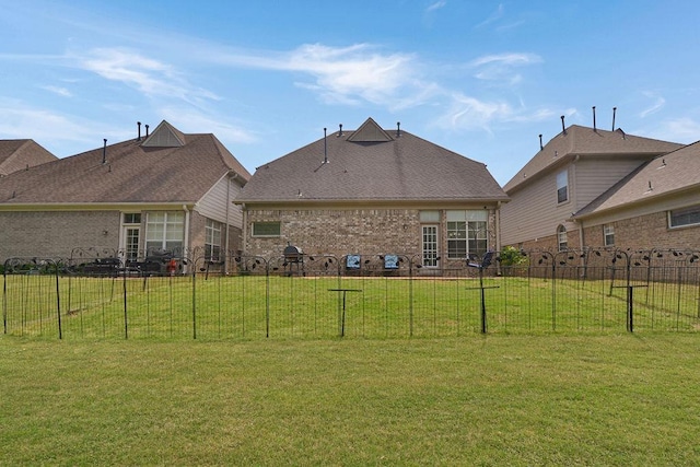 rear view of property featuring a yard, brick siding, and fence