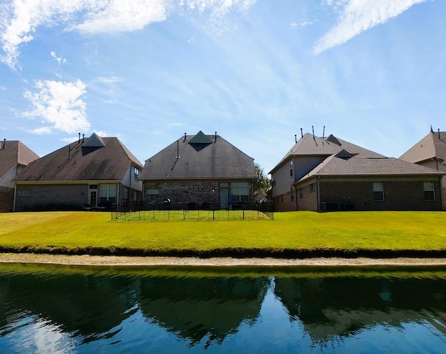 rear view of house with a yard and a water view