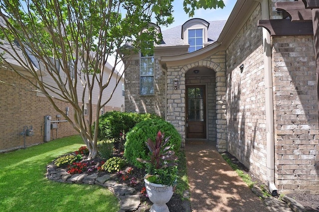 doorway to property with brick siding and a yard