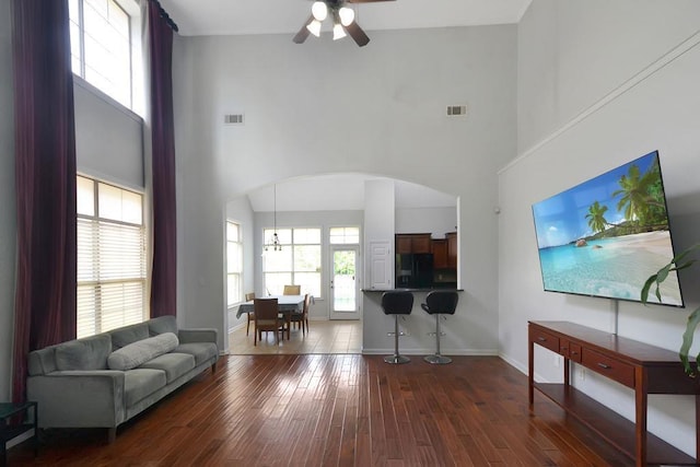 living room with visible vents, arched walkways, dark wood-type flooring, and baseboards