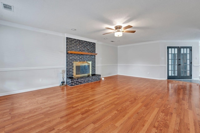 unfurnished living room featuring visible vents, light wood finished floors, baseboards, a fireplace, and crown molding