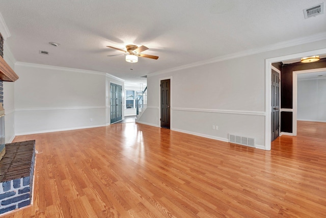 unfurnished living room featuring visible vents, a fireplace, a ceiling fan, and light wood-style floors