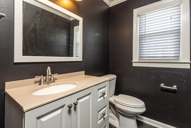 half bathroom with vanity, toilet, and baseboards