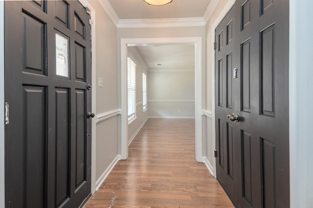 entryway with light wood finished floors, crown molding, and baseboards