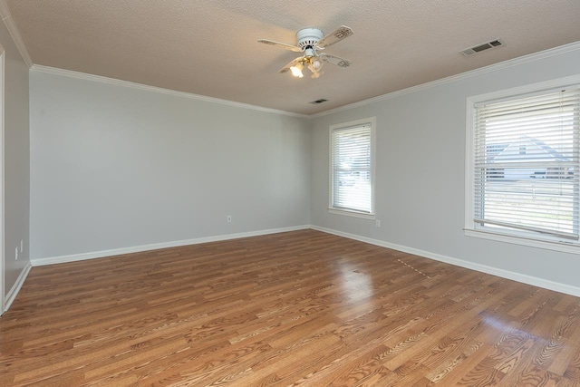 unfurnished room with wood finished floors, baseboards, visible vents, ceiling fan, and ornamental molding