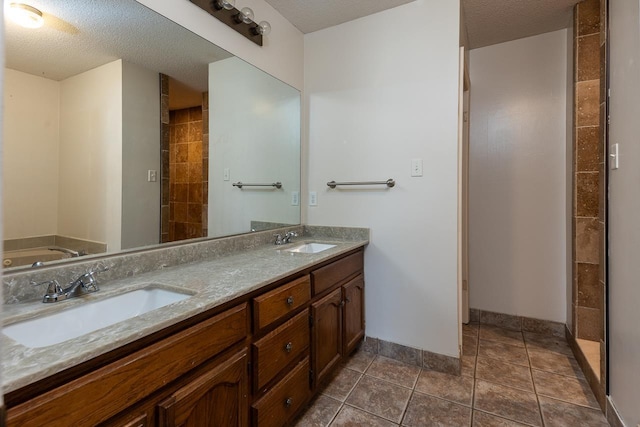 full bath featuring a sink, a textured ceiling, and tile patterned floors