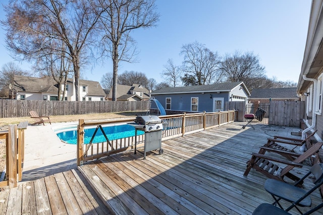 wooden terrace with area for grilling, a fenced in pool, a residential view, and a fenced backyard